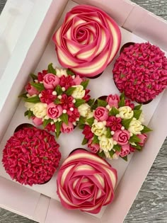 cupcakes decorated with pink and white flowers in a box