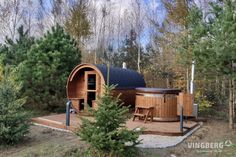 an outdoor hot tub in the middle of some trees and grass with chairs around it