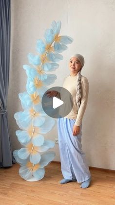 a woman standing next to a tall blue flower