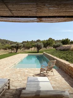 an outdoor pool with chaise lounges next to it and olive trees in the background