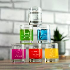 four shot glasses filled with different colored liquids