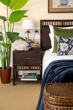 a bedroom with a bed, nightstand and plant in it