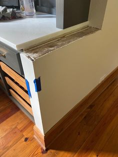 a kitchen counter that has been painted white with blue tape around the edges and drawers