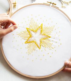 someone is stitching a star with yellow thread on a white surface next to other items