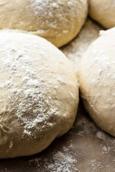 several uncooked doughnuts sitting on top of a baking sheet covered in powdered sugar