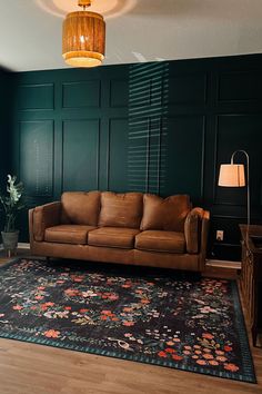 a brown leather couch sitting on top of a wooden floor next to a green wall