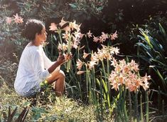 a woman sitting in the grass next to flowers