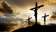 three crucifixs on top of a hill with clouds in the background