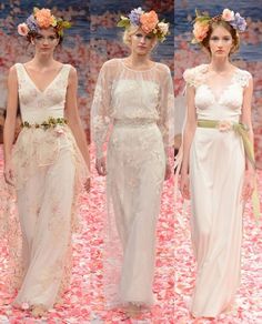 three models walk down the runway in white gowns with flowers on their headbands