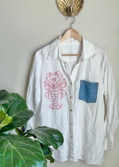 a white shirt hanging on a wall next to a potted plant