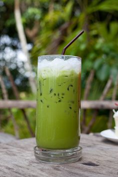 a green drink sitting on top of a wooden table