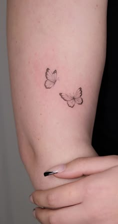 a woman's arm with two small butterflies on the left side of her arm