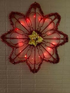 a red flower shaped light up decoration hanging on a brick wall with lights around it