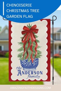 christmas tree garden flag with red ribbon hanging from it's pole in front of a house