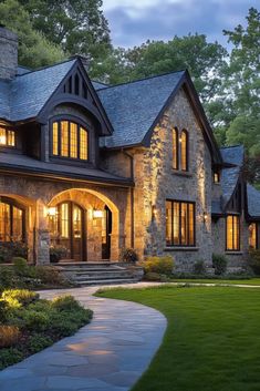 a stone house lit up at night with lights on the front windows and walkway leading to it