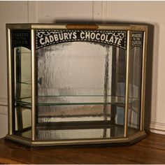 an old fashioned caddy's chocolate display case sitting on a wooden table next to a wall