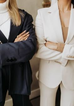 two women standing next to each other with their arms crossed