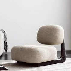 a white chair sitting on top of a wooden floor next to a black and white rug