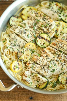 chicken and zucchini pasta in a pan with lemons, parmesan sprinkled on top