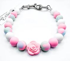 a pink and white bracelet with a rose on it's center beaded in plastic beads