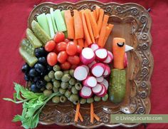 a platter with carrots, radishes, cucumbers and other vegetables