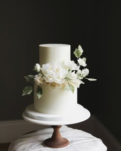 there is a white cake with flowers on the top and bottom tier, sitting on a table