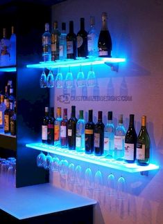 several bottles of wine are lined up on the shelves in a bar with blue lights