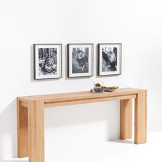 a wooden table with three pictures on the wall