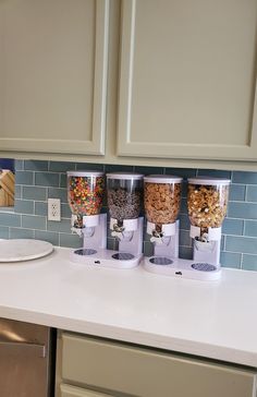 three cups with cereal in them are sitting on the counter next to a dishwasher