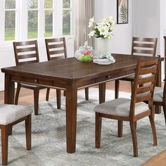 a dining room table with chairs and a vase filled with flowers on top of it