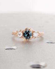 a blue diamond ring sitting on top of a white surface with three diamonds around it