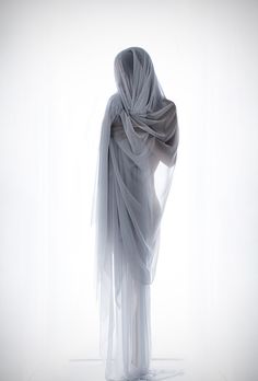 a woman in white dress with veil on her head and legs, back to camera