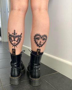 the legs of a woman with tattoos and boots on her feet, both wearing black rubber boots