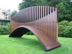 a large wooden sculpture on top of a lush green field