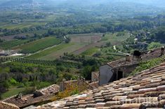 an aerial view of the countryside and rolling hills from a roof top in italy, looking down on some buildings