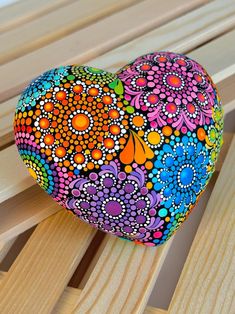 a painted heart sitting on top of a wooden bench