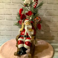 a santa clause figurine sitting next to a christmas tree