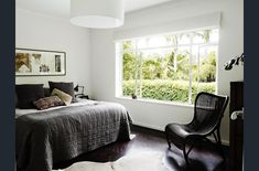 a bedroom with a bed, chair and large window in it's center area