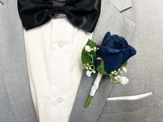 a man wearing a gray suit with a blue rose boutonniere on his lapel