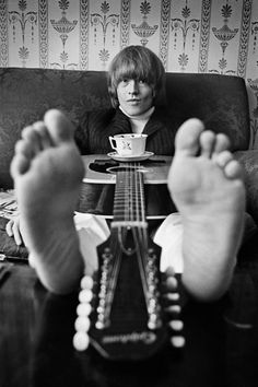 a person sitting on a couch with their feet propped up in front of a guitar