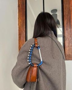 the back of a woman's jacket with beads and chains hanging from it, in front of a window