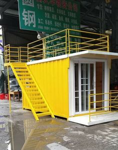 a yellow and white building with stairs next to it's entrance in an industrial area