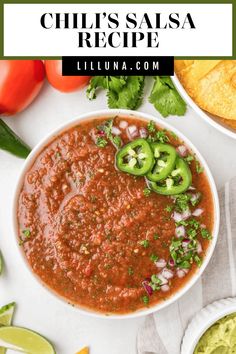 a bowl filled with chili sauce and topped with sliced jalapenos next to guacamole chips