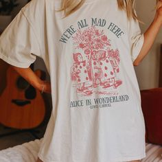 Get ready to be OBSESSED with your new Alice in Wonderland Lewis Carroll Mad Hatter shirt. It's the cutest and most trendy way to combine all those important trendy dark academia and literature shirt vibes! This is the perfect disneyworld shirt!  * Q U I C K * F A C T S * ✺  All shirts are UNISEX ✺  100%  ringspun cotton (fiber content may vary for different colors) ✺  Soft-washed, garment-dyed fabric brings extra coziness ✺  Wash and dry normally (on cool for best results) ✺  Sewn-in twill label * S I Z I N G * ✺ For an oversized fit, select two or three sizes up from your normal size ✺ Model is wearing size L  ✺ Sizing runs true to size ✺ Relaxed fit ✺ Most women find their typical size works best, since they are meant to fit a touch loose ✺ See Size guide and fit in images          * S Alice In Wonderland T Shirt, Relaxed Fit Bookish Tops With Text Print, Bookish Relaxed Fit Graphic Print Top, White Bookish Top With Funny Print, Bookish Graphic Print T-shirt For Summer, Summer Bookish T-shirt With Graphic Print, Bookish Short Sleeve Tops For Spring, Bookish Short Sleeve Screen Print Tops, Bookish Style Letter Print Summer Tops