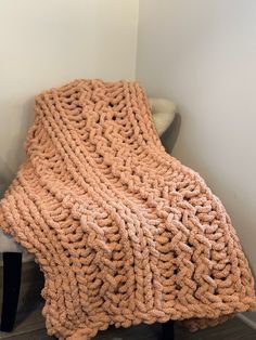 an orange knitted blanket sitting on top of a chair