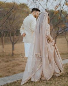 a man and woman standing next to each other in front of trees with their backs turned