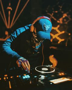 a dj mixing music on his turntable with headphones and gloves around his neck