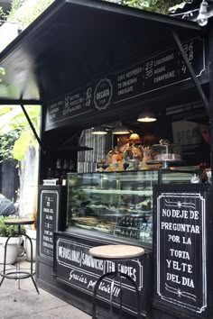 the outside of a restaurant with tables, chairs and signs on the side of it