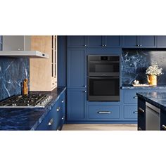 a kitchen with blue cabinets and an oven in the center is seen from across the room