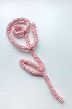 a pink crocheted rope on a white surface with the end knoted together